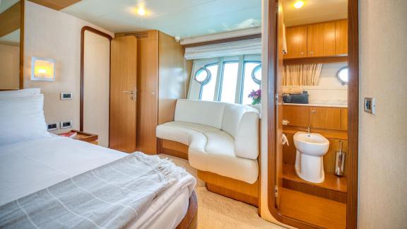Ferretti 681 Dominique features a cabin with a double bed, seating area and access to a private bathroom.