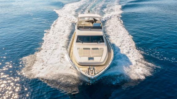 Ferretti 681 Dominique is seen cruising across open waters with its foredeck and foamy wake in view.