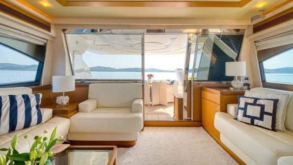 Ferretti 681 Dominique features a bright saloon with large windows, comfortable seating and aft deck access.