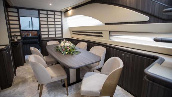 Among Athens yacht rental options Sofia D interior shows dining table with seating in modern style.