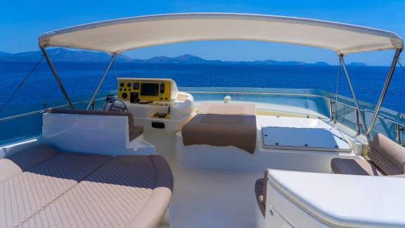 Among Athens yacht rental options Sofia D flybridge shows helm and seating area with open sea view.