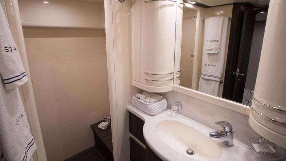 Among Athens yacht rental options Sofia D bathroom shows sink, mirror and storage space with modern layout.