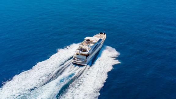 Among Athens yacht rental options Sofia D is seen from above cruising fast with wide wake in deep blue sea.