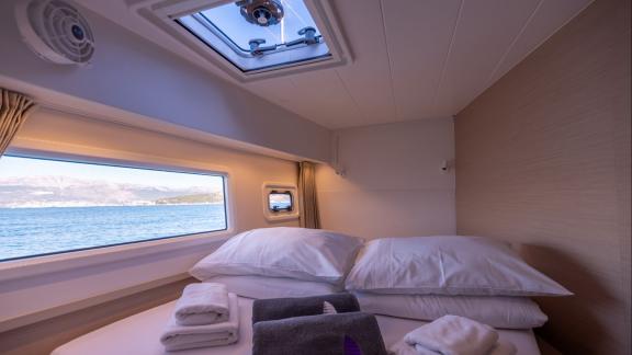 In Kastela bareboat catamaran charter Find Us guest cabin with bed, pillows and towels for comfortable stay.