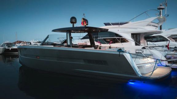 The Bombon motor yacht is moored in the marina, illuminated by blue underwater lights.