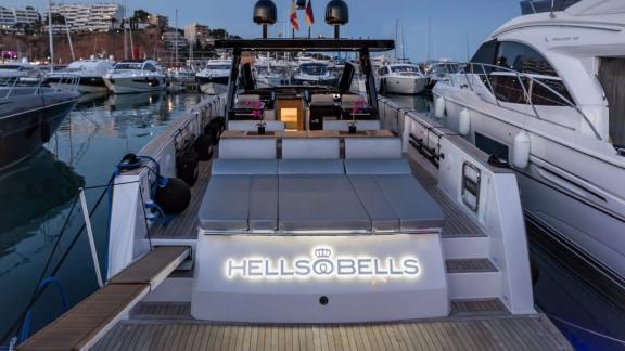 The Bombon motor yacht is docked at the marina, featuring a spacious cushioned seating area on the aft deck.