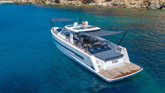 Vor Mallorca liegt die Motoryacht Petitchet mit geöffneten Sonnendächern in klarem Wasser nahe der Küste.