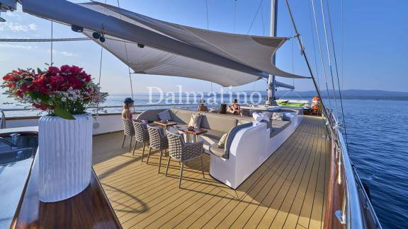 Eleganter Sitzbereich an Deck der Dalmatino-Yacht mit schattenspendendem Sonnensegel und blühender Vase.