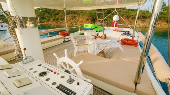 The steering deck of the gulet Vega with a set table, seating and water sports equipment, surrounded by calm waters and