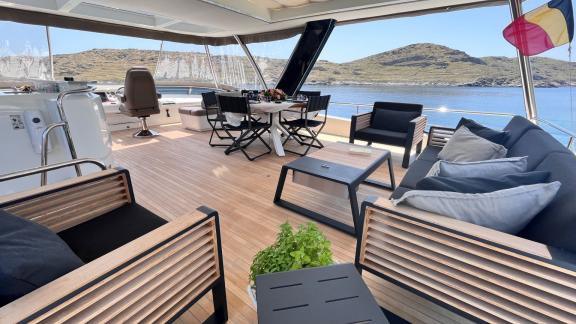 A cozy lounge deck on a luxurious catamaran, furnished with modern seating, offers a stunning view of the sea.