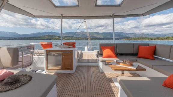 Elegant outdoor lounge on the Serenissima catamaran with views of the sea and mountains.