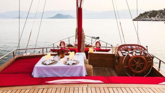 Elegant gedeckter Tisch auf dem Deck einer Yacht, umgeben von ruhigem Meer und Kerzenlicht.