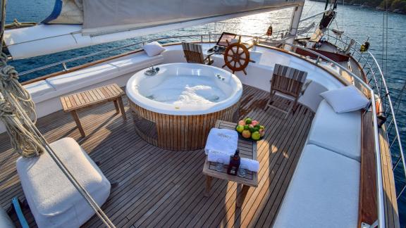 Sailing yacht with a whirlpool, seating and a table with fruit and drinks.