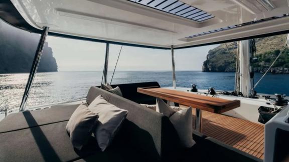 Cushioned seating and table overlook the sparkling bay in soft afternoon light.