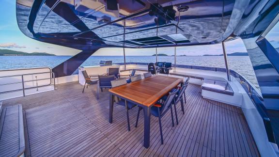 Evita power catamaran features a dining table, lounge seating and wide sea views on the flybridge.