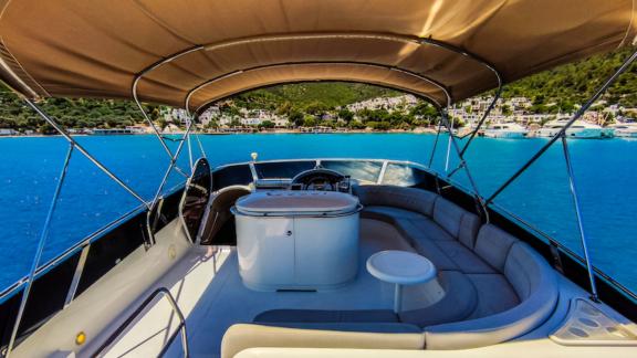 Flybridge-Sitzbereich der Motoryacht Zeus 2 mit Blick auf das blaue Meer und die grünen Berge.