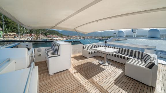 Der geräumige Sitzbereich auf dem Oberdeck der Yacht Opera bietet eine komfortable Entspannung mit Blick auf den Yachtha