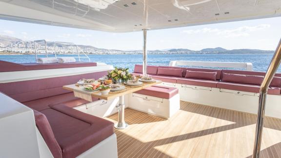 Covered dining area with a set table and sea view on the King of Diamonds in Athens.