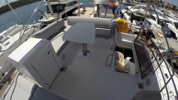 The upper deck of motor yacht Brigadoon features a table and seating area.