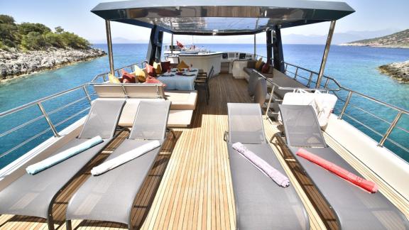 The upper deck of the trawler Compass features sun loungers and a comfortable seating area.