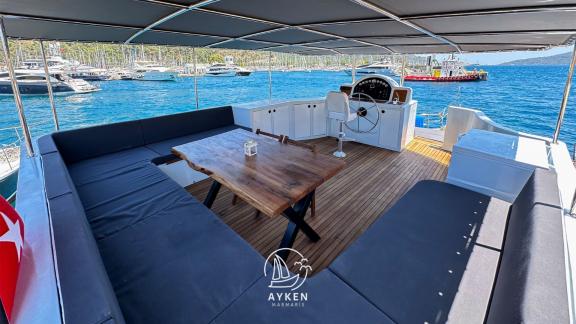 The upper deck of Gulet Ayken features a spacious seating area and helm, perfect for a comfortable cruise.