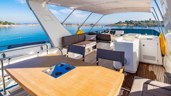 The upper deck of Blue M motor yacht in Mallorca features seating and dining area.