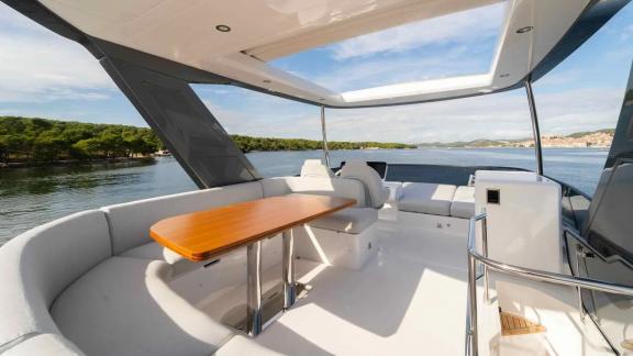 U-shaped seating and table on Leeloo yacht’s flybridge with panoramic sea views.