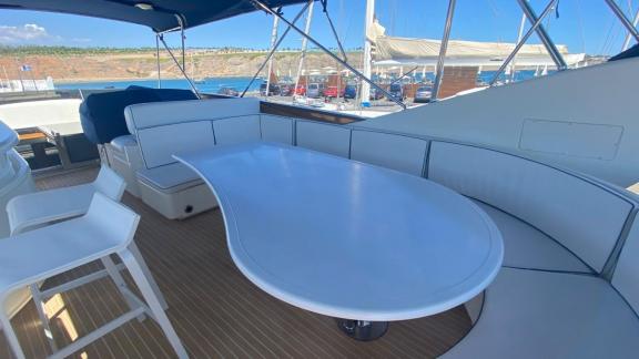 The flybridge of motor yacht Riva 21 features a comfortable seating area and a large table.