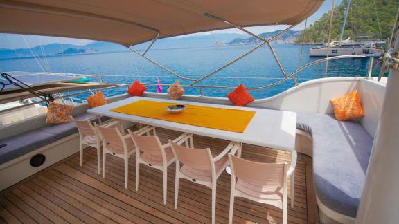 The dining area on the deck of the gulet Queen of RTT in Fethiye offers a long table with comfortable seating and colour