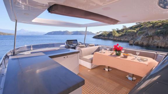 The flybridge features a kitchen and an elegant dining table with a sea view.