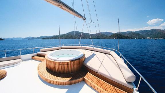 A whirlpool on the deck of a gulet, with a view of the open sea and the surrounding mountains.