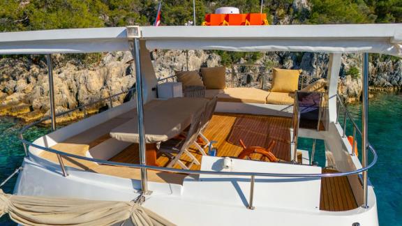 The relaxation area on the upper deck of Gulet ÇağAy offers cozy seating and sunshade in a scenic bay.