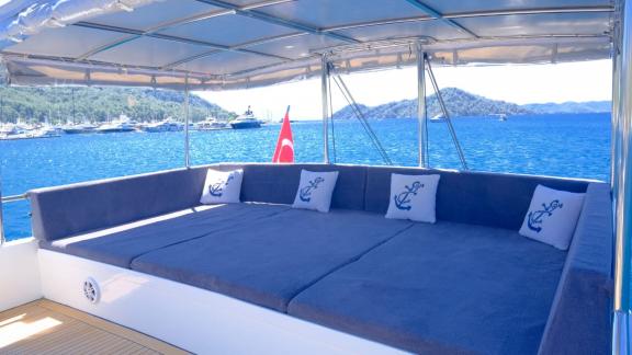 The cozy lounge area offers shade and comfortable seating with views of the deep blue sea and surrounding mountains.