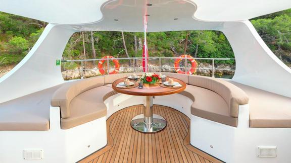 Eleganter Essbereich mit Waldblick auf dem Deck der Belgin Sultan, ideal für eine wöchentliche Yachtcharter in der Türke