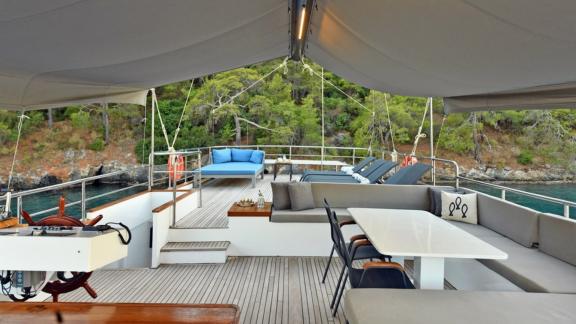 The expansive deck of Gulet Nayk 2 features luxurious seating and sun loungers in a serene setting.