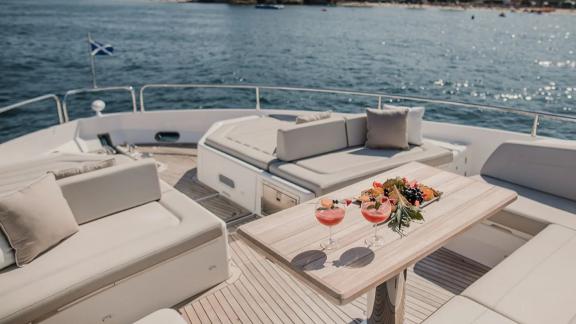 The bow area of Lady M in Mallorca features cushioned seating and drinks on the table.
