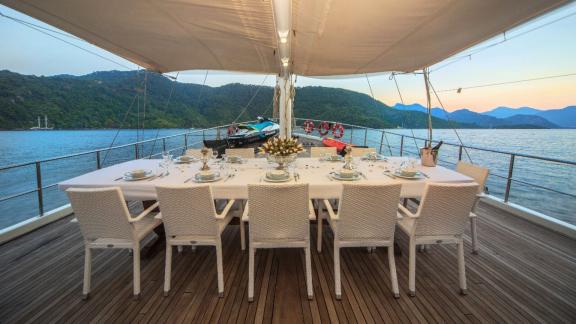 Gedeckter Esstisch auf dem Deck einer Gulet mit Meerblick.