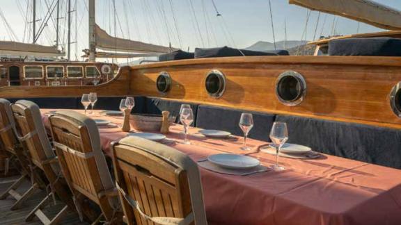 Ein elegant gedeckter Esstisch auf dem Deck einer traditionellen türkischen Gulet im Hafen von Bodrum, Türkei.