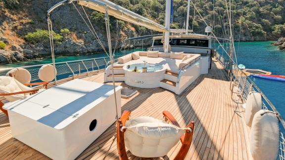 The spacious sun deck of the Gulet Tarkan 5 in Fethiye, equipped with sun loungers, a whirlpool and surrounded by crysta