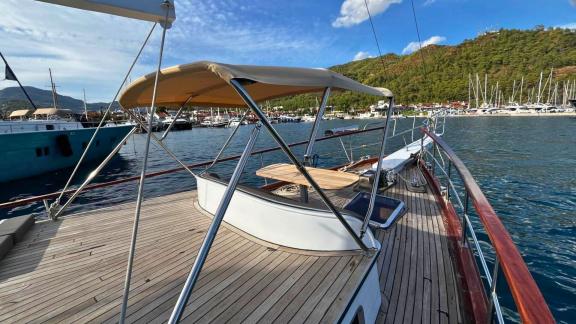 Gulet Ahmet Ertürk anchored at the harbor, with a shaded seating area and table on the front deck.