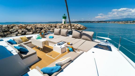 Spacious lounge and sunbathing area at the front of a Bali catamaran with a view of the sea and lighthouse.