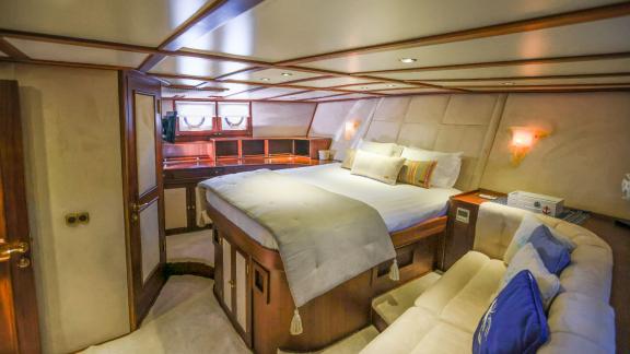 Gazella’s master cabin features a large bed, a seating area, and wooden details.