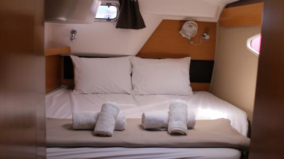 Double bed in a cabin on Catamaran Ayda1 with white pillows and folded towels.