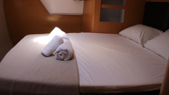 Double bed in a cabin on Catamaran Ayda1 with folded towels on the blanket.