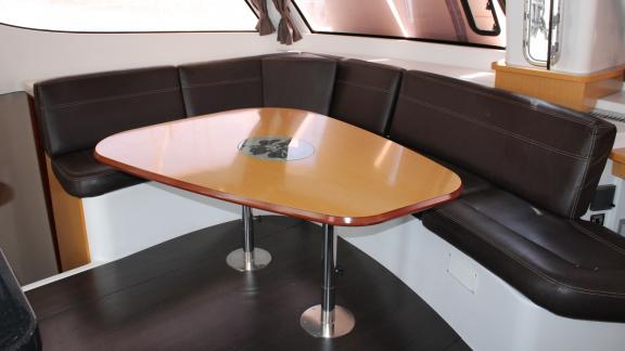 Wooden table with black leather seating in the dining area of Catamaran Ayda1.