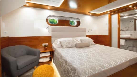 Стильная каюта с уютной кроватью, креслом и современной ванной комнатой на Son de Mar в Сплите, Хорватия.