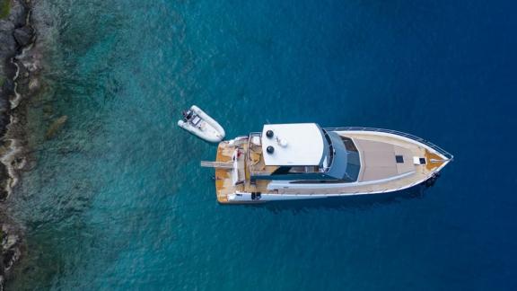 Foto der Motoryacht Golden Blue aus der Vogelperspektive, verankert in ruhigen Gewässern mit einem kleinen Boot daneben.