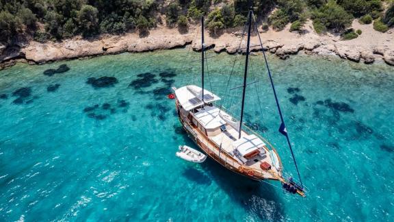 Die Gulet Golden Joy in kristallklarem Wasser, umgeben von einer wunderschönen Küstenlinie in Bodrum.