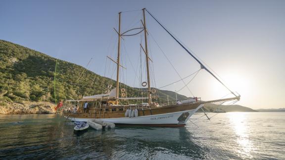 This breathtaking shot captures the Gulet Golden Life by an idyllic coastline during sunset.