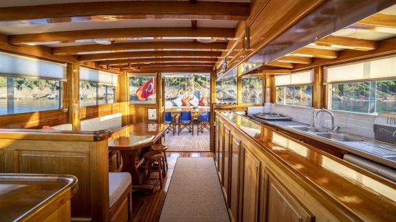 The interior shows a kitchen, dining table, and the exit to the aft deck with a Turkish flag.